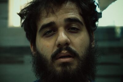 Cinematic close-up of a bearded man with tired eyes and moody lighting, 6 meses 1.