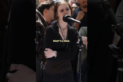Woman speaking into a microphone at a public event, acting as a argumentere
