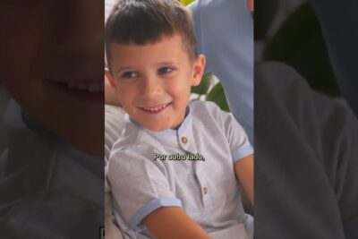 Smiling young boy seated on a sofa with a visible Portuguese subtitle, a clonagem 8