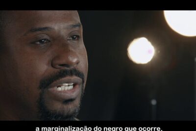 Close-up interview speaker with the phrase a discriminacao visible in on-screen subtitles