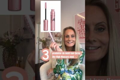 Smiling woman holding a pink Sky High mascara tube demonstrating how to a fjerne mascara