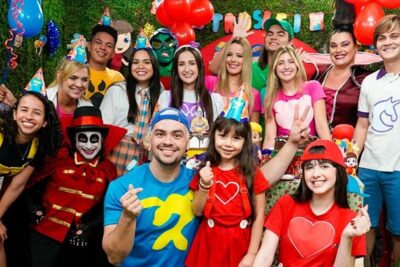 Group of smiling children and adults in bright costumes and party hats at a colorful birthday celebration a gi 1.