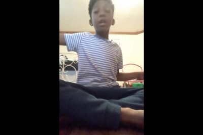 Child sitting cross-legged in a striped shirt, a spise candid indoor portrait