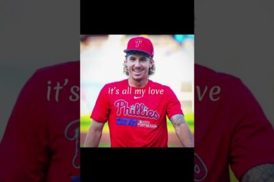 Smiling person in red Phillies shirt and cap with 'it's all my love' overlay, a stotte casual portrait.