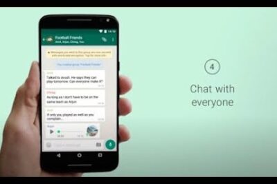 Hand holding smartphone displaying a whatsapp group chat screen with messages and a voice note