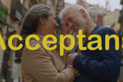 Mature couple smiling and embracing on a city street representing acceptera sjalv.
