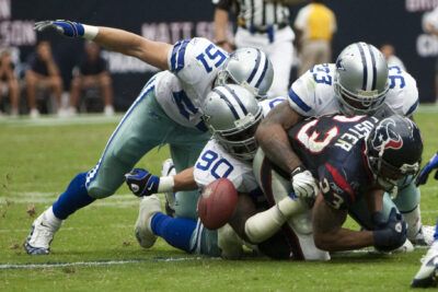 Adrenalinfylld close-up of a runner being tackled as the football comes loose