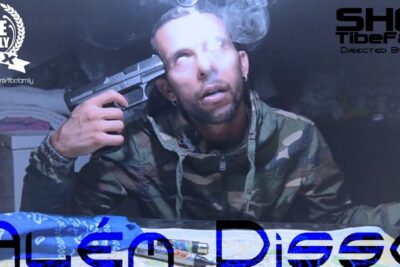 Man in camouflage jacket holding a handgun to his temple with smoke rising, promotional image for alem disso 22.
