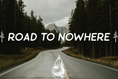 Winding mountain road through dense pine forest under an overcast sky with 'Road to Nowhere' lettering and alternative former emblem.