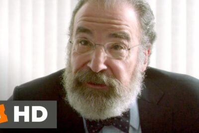 Close-up of an older bearded man in glasses appearing engaged in an argument mobbing situation