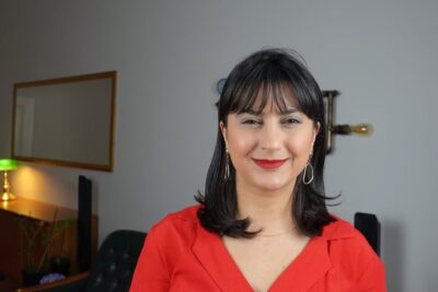 Portrait of a smiling woman in a red blouse in a living room setting discussing argumente rassendiskriminierung