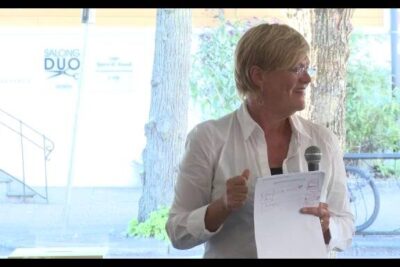 Presenter holding microphone and notes under a canopy, suitable for assistert reproduksjon informational use