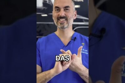 Smiling clinician in blue scrubs demonstrating hand gestures for asthetische operationen 1