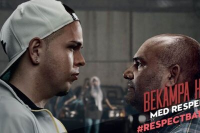 Two men face each other in a tense confrontation with visible campaign text to bekampa rasism