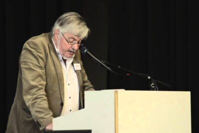 Presenter at a lectern delivering a talk on besonderem bildungsbedarf