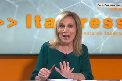 Female TV presenter in a studio holding a pen suitable for bevande alcoliche topics