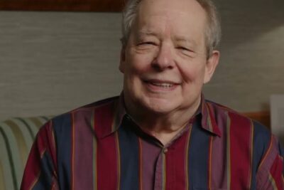 Elderly man smiling in a colorful striped shirt, bidra a warm, approachable portrait