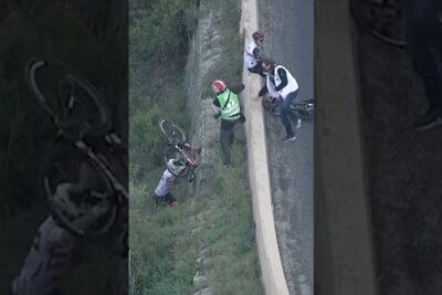 Cyclists retrieving a fallen bicycle from a roadside embankment, brug cyklen