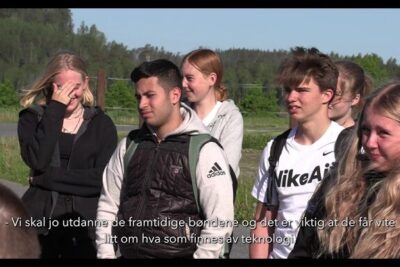Group of young students outdoors listening attentively to a demonstration about how to bruk droner in farming