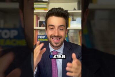 Smiling suited presenter gesturing in front of a bookshelf while a caption refers to cambio hora 3.