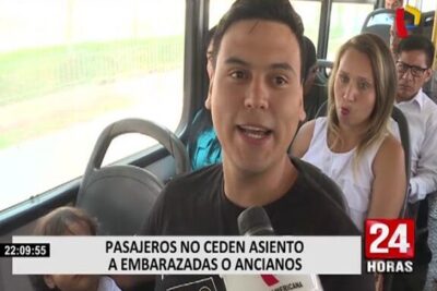 Man speaking into a microphone on a crowded bus about passengers refusing to ceder asiento