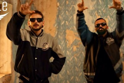 Two men in sunglasses and bomber jackets pose in a gritty indoor music-video set suggesting a chat gpt inspired aesthetic.