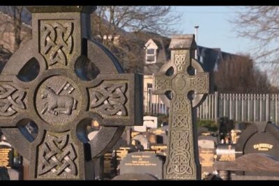 Carved Celtic stone crosses marking graves in a chiesa cattolica cemetery.