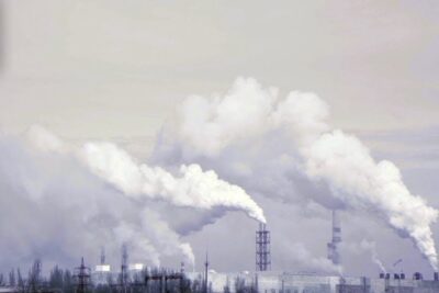 Large industrial smokestacks emitting thick white plumes over a factory landscape, highlighting climate change 1.