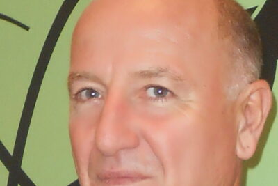 Close-up portrait of a middle-aged professional man against a green background suitable for clonazione riproduttiva pro e contro della clonazione umana coverage.