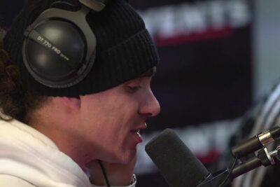 Person wearing headphones speaking into a studio microphone for code penal podcast
