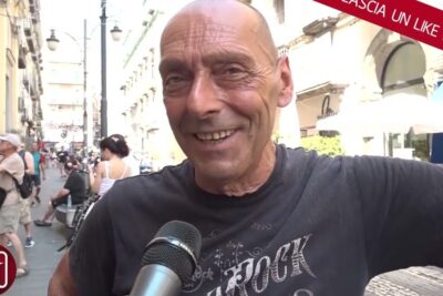 Smiling man interviewed on a busy pedestrian street discussing commercio aperto