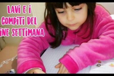 Young child writing in a squared notebook at a desk completing compiti casa 3.