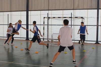 Students playing indoor handball in a school gym during practice considerado esporte 1.