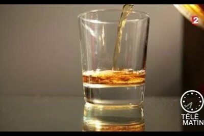 Shot glass being filled with amber liquor illustrating consommation dalcool
