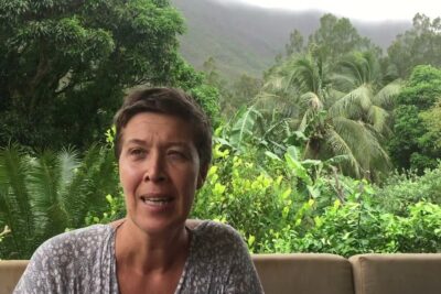 Person seated on a patio surrounded by lush tropical plants, implying relaxed lifestyle and consommer fromage