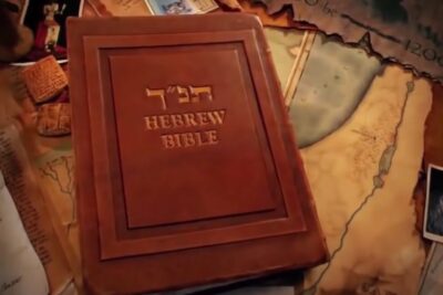 Leather-bound Hebrew Bible embossed with Hebrew letters resting on an antique map and scattered documents, contrarie bibbia