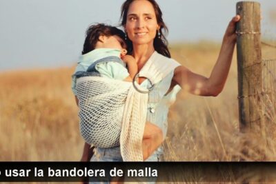Woman carrying a sleeping child in a mesh ring sling demonstrating crianza natural