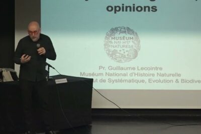 Speaker presenting in front of a projected slide highlighting croyances opinions during a lecture
