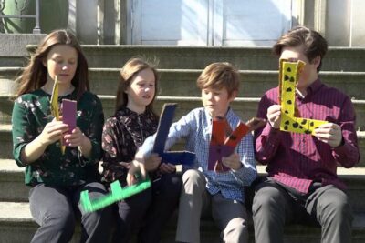 Four children sitting on stone steps holding colorful handmade letter props, danske kongehus.
