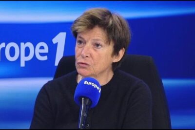 Woman speaking into a blue Europe 1 microphone in a radio studio during a debat lavortement related interview