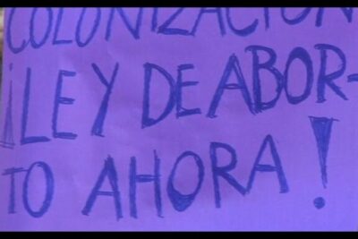 Purple handwritten protest sign in Spanish calling for abortion law change and decriminalisation lavortement.