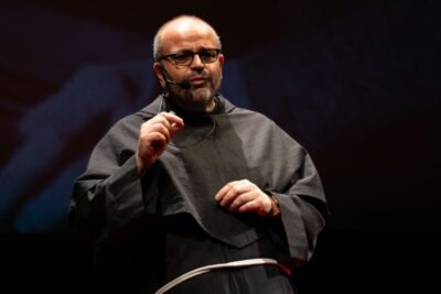 Robed speaker with headset microphone on stage presenting dellintelligenza artificiale 1