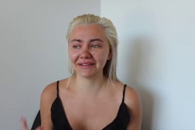 Tearful candid portrait of a person with wet blonde hair and black top, der ogsa