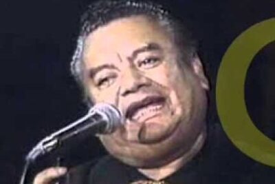 Close-up portrait of a male vocalist singing into a microphone during a stage performance, derecho vida 10.