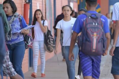 Group of students walking along a school corridor between classes, illustrating themes for desempenho alunos research.