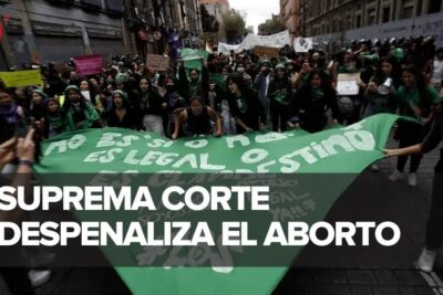 Demonstrators in a street march holding a large green banner and signs calling for despenalizacion aborto 2.