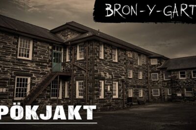 Sepia-toned exterior of a multi-windowed stone building with an exterior staircase and signage, det ocksa.