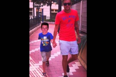 Man in red shirt and child in blue shirt walking hand in hand along a sunlit tiled path det vigtigt 26