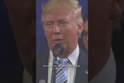Blond male speaker at a microphone with visible subtitle 'pocahontas', dibattito razzismo