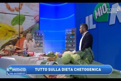 Two presenters beside a table of fresh vegetables, nuts and keto foods discussing dieta chetogenica 2.